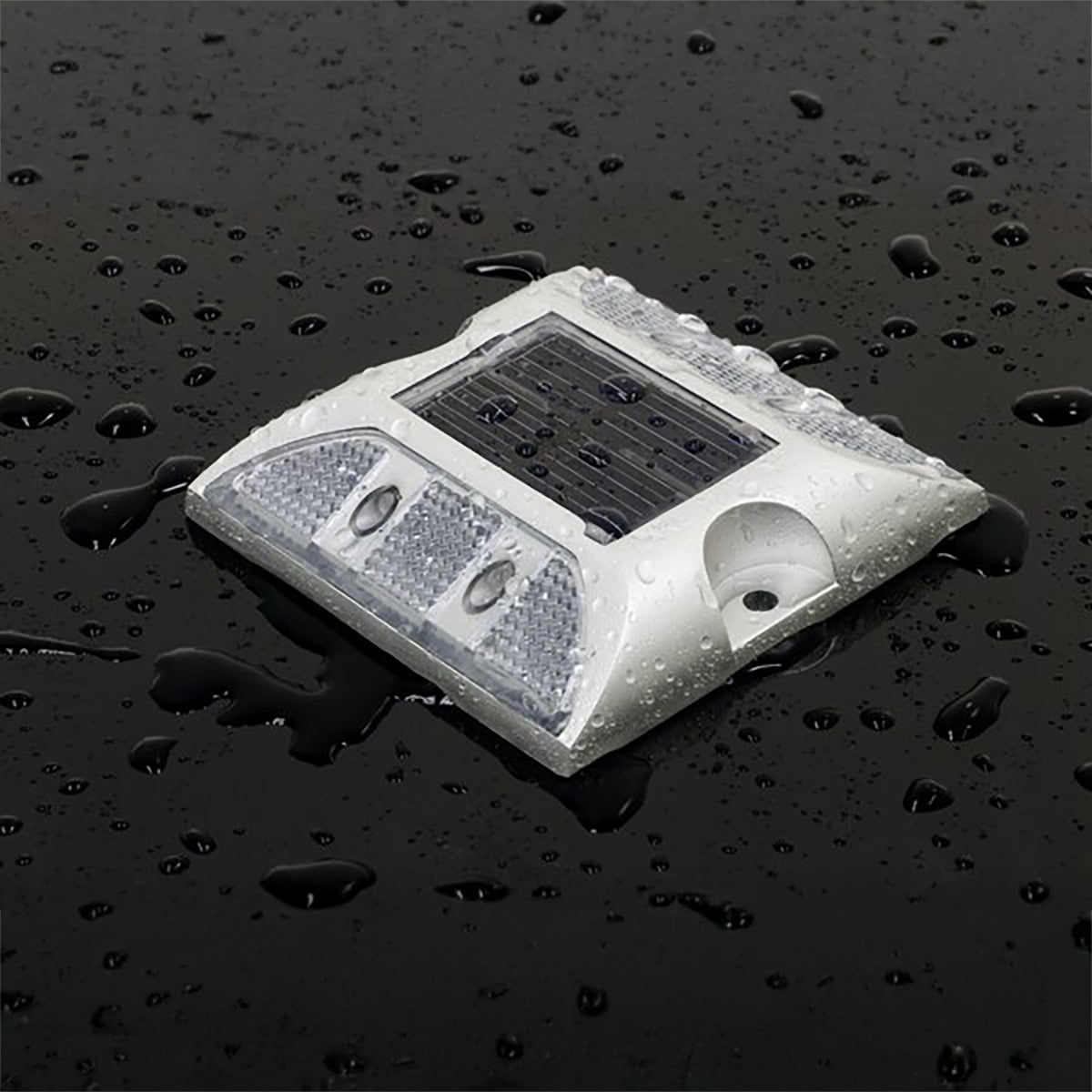 Solar-powered LED light on a wet surface with water droplets.