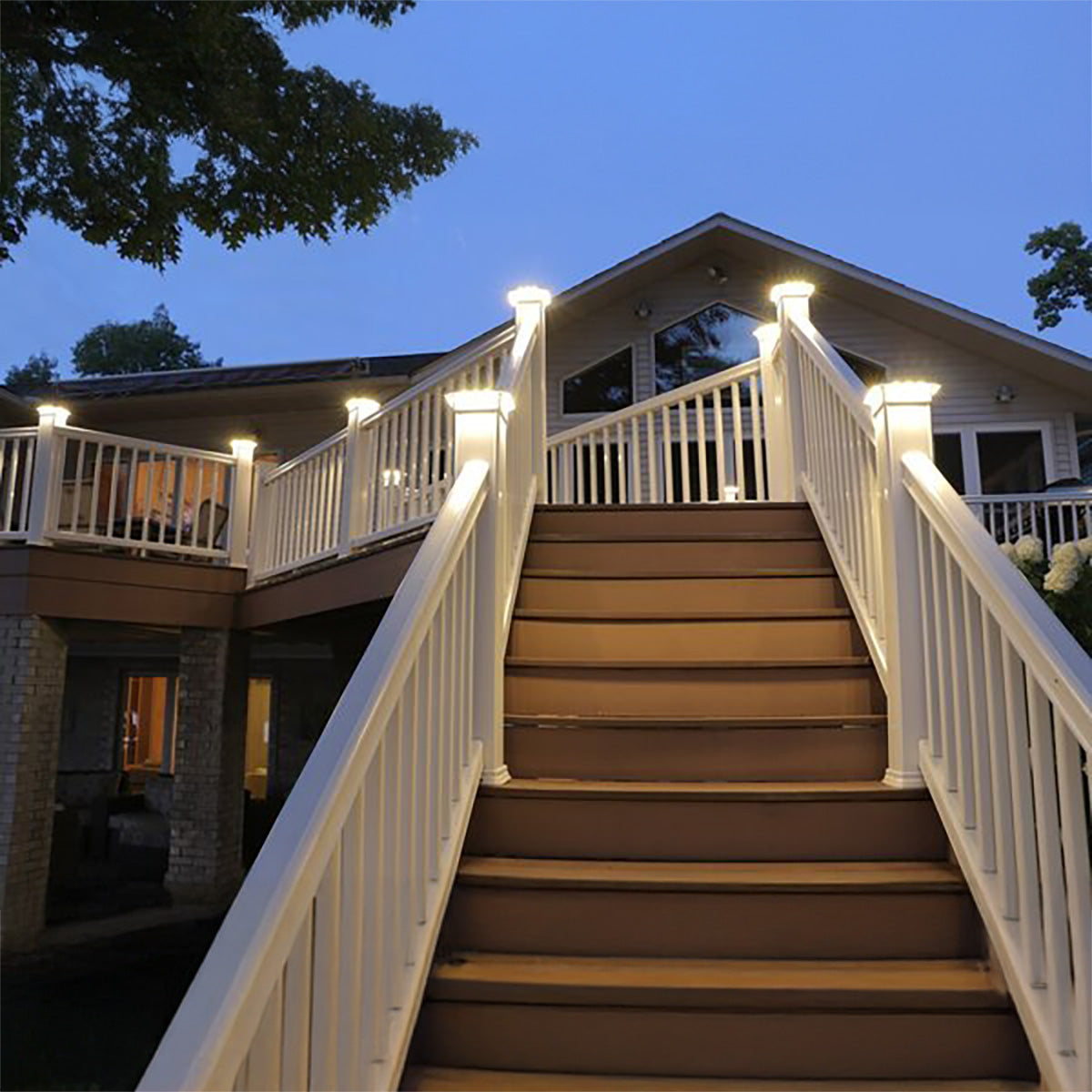Staircase leading to a house with illuminated railings at night.