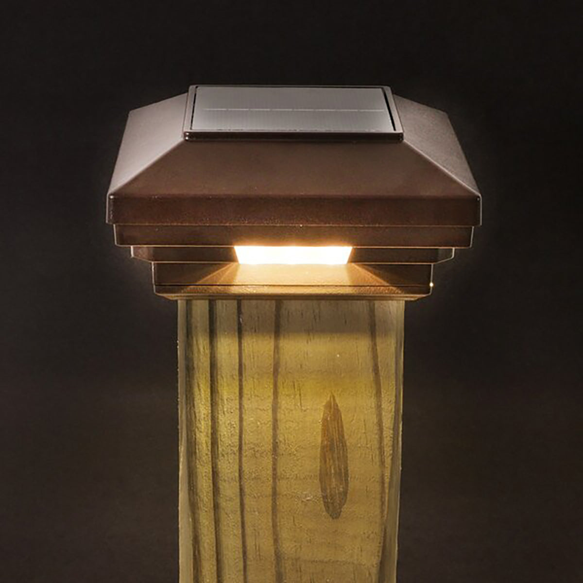 Solar-powered outdoor light fixture on a wooden post against a dark background