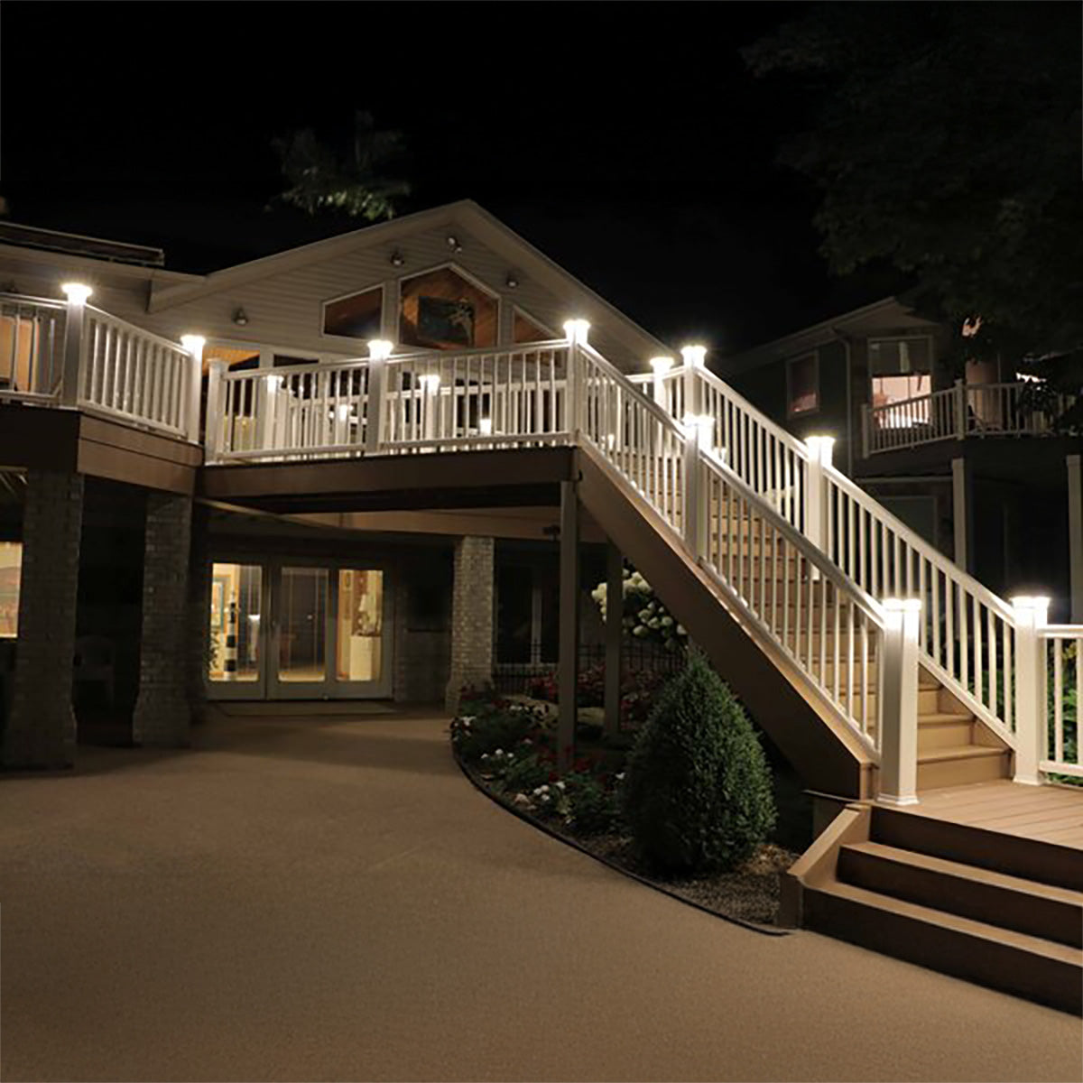 House exterior with a staircase and deck illuminated by lights at night.