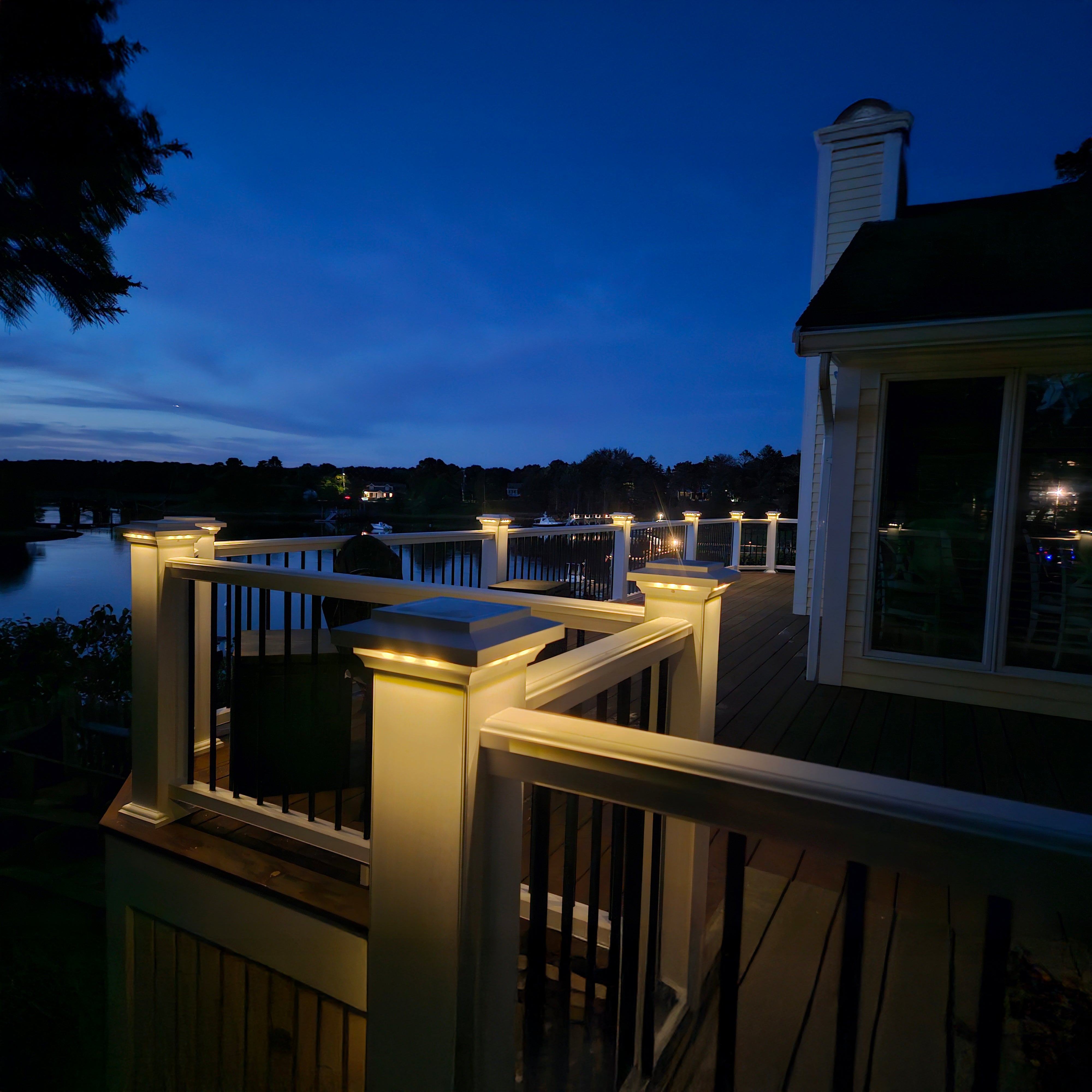 Deck with railing lights overlooking a body of water at night