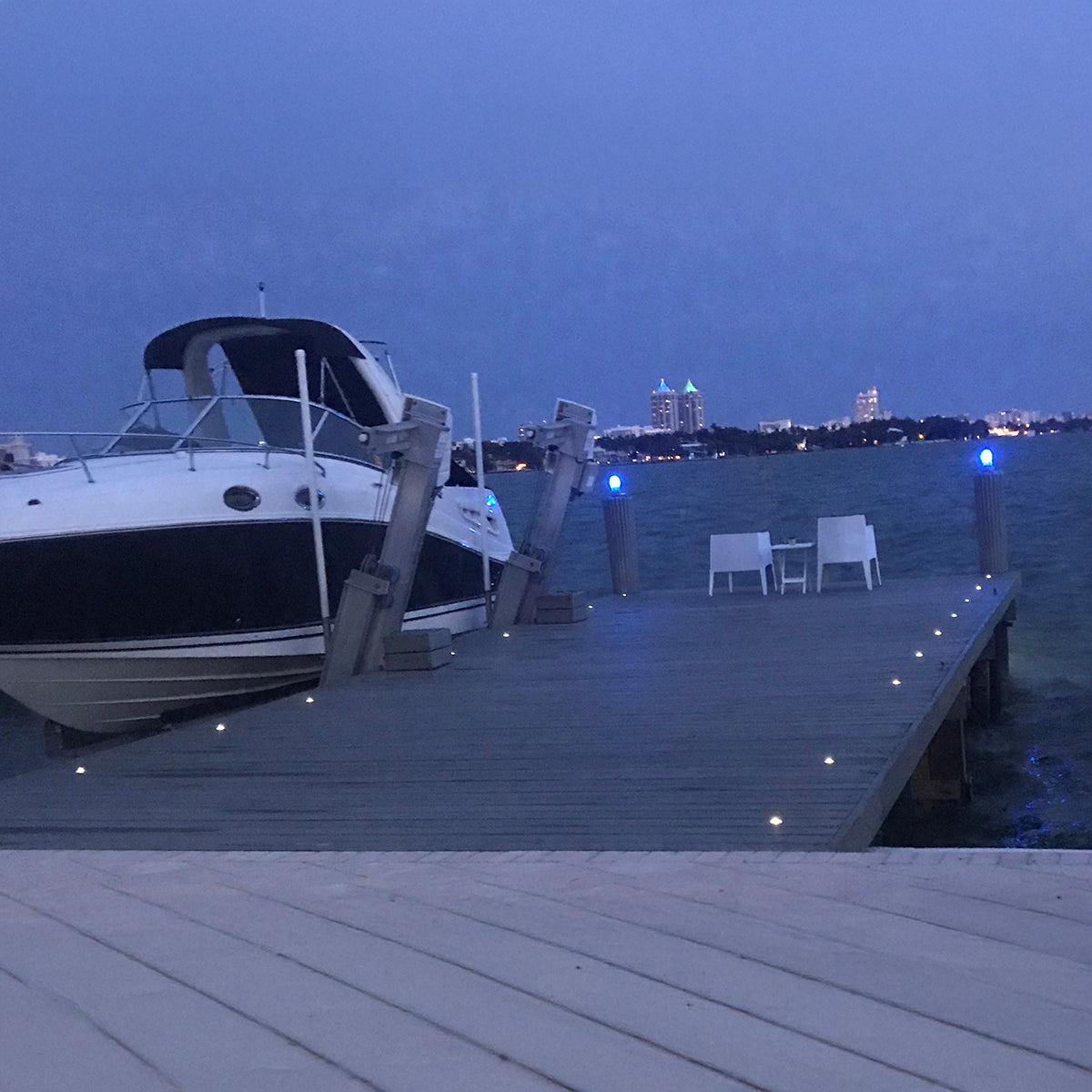 Boat docked at a pier with city skyline in the background during evening.