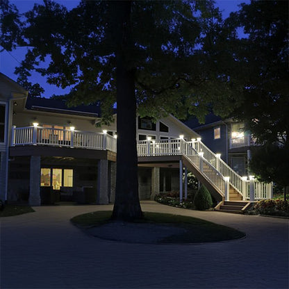 House exterior with a staircase and deck illuminated by outdoor lights at night.