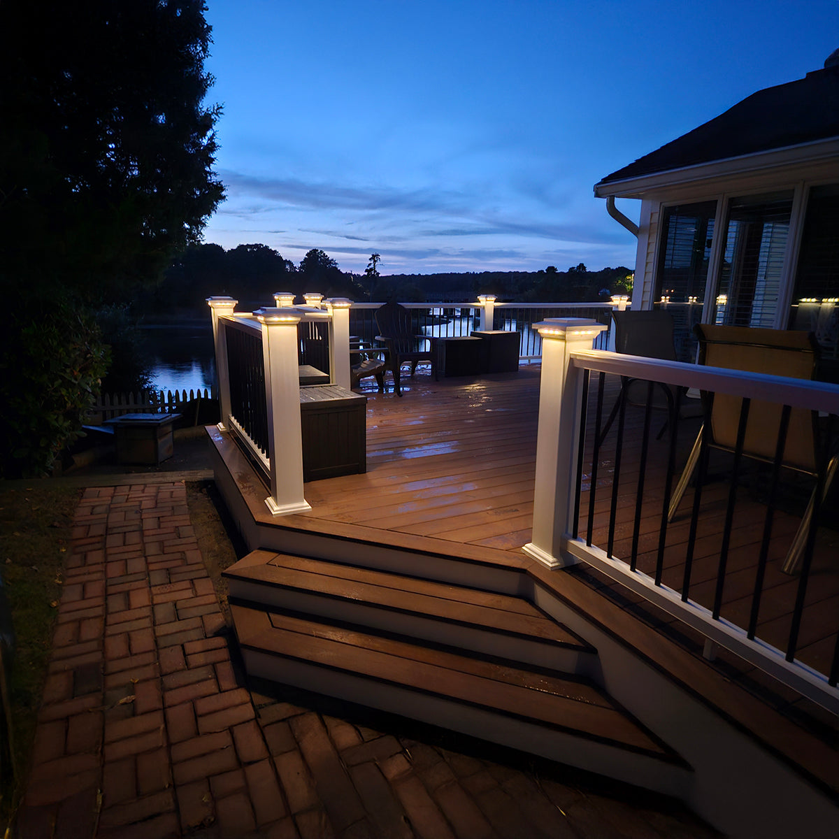 Wooden deck with outdoor furniture and lighting at dusk.
