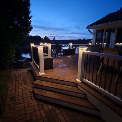 Wooden deck with outdoor furniture and lighting at dusk.