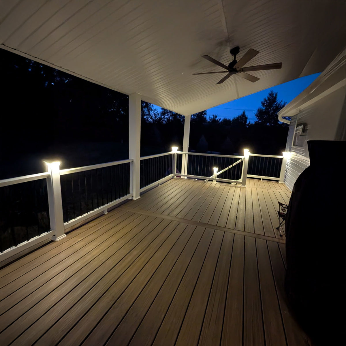 Wooden deck with ceiling fan and string lights at night