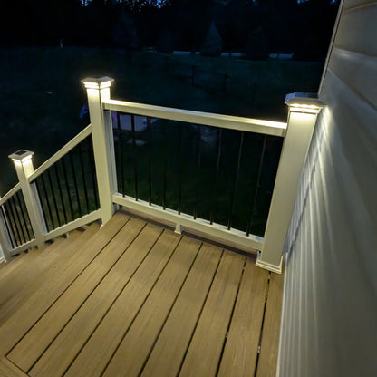Wooden deck with white railings and solar lights at night