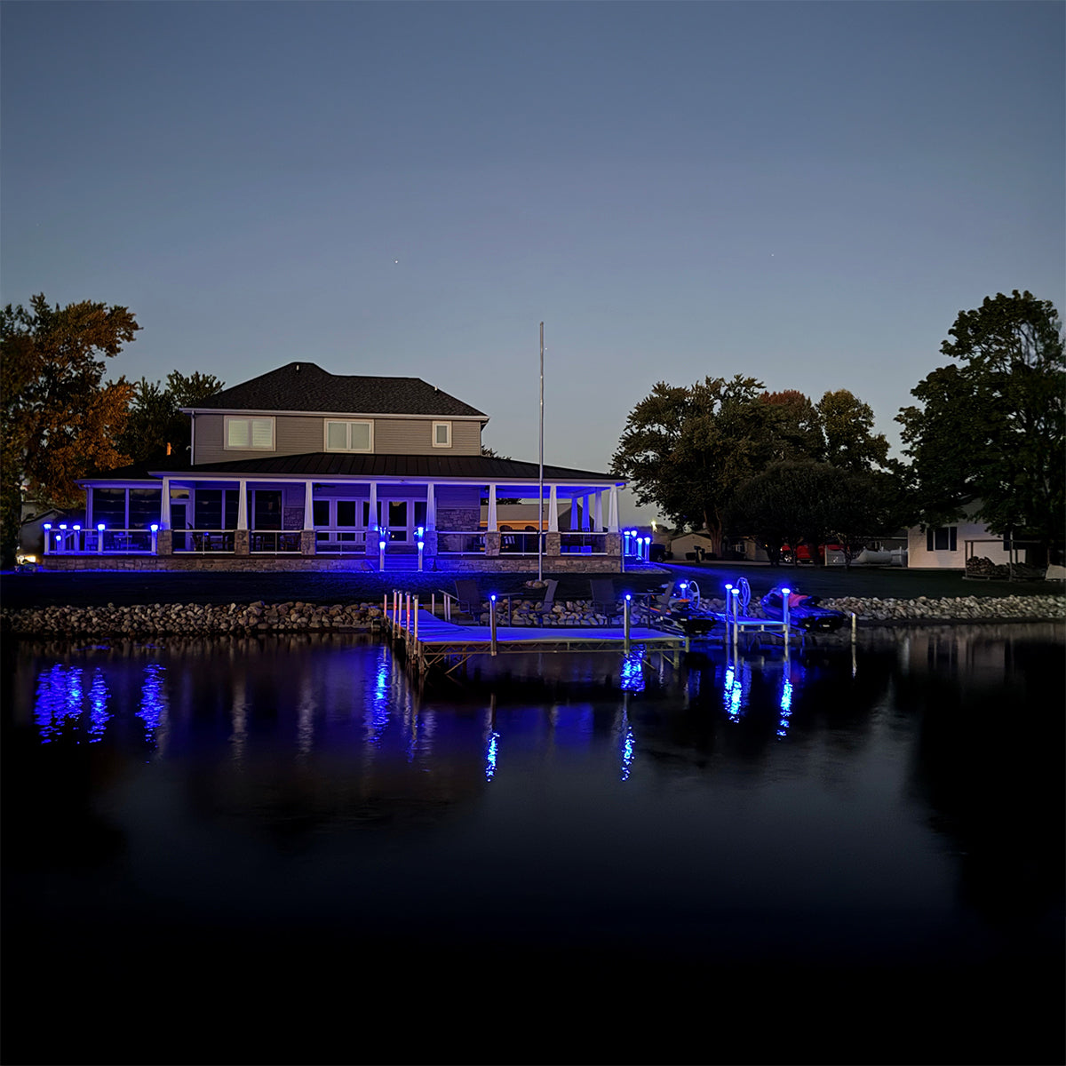 Evening view of a waterfront house with dock lights reflecting on water