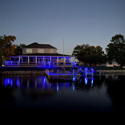 Evening view of a waterfront house with dock lights reflecting on water