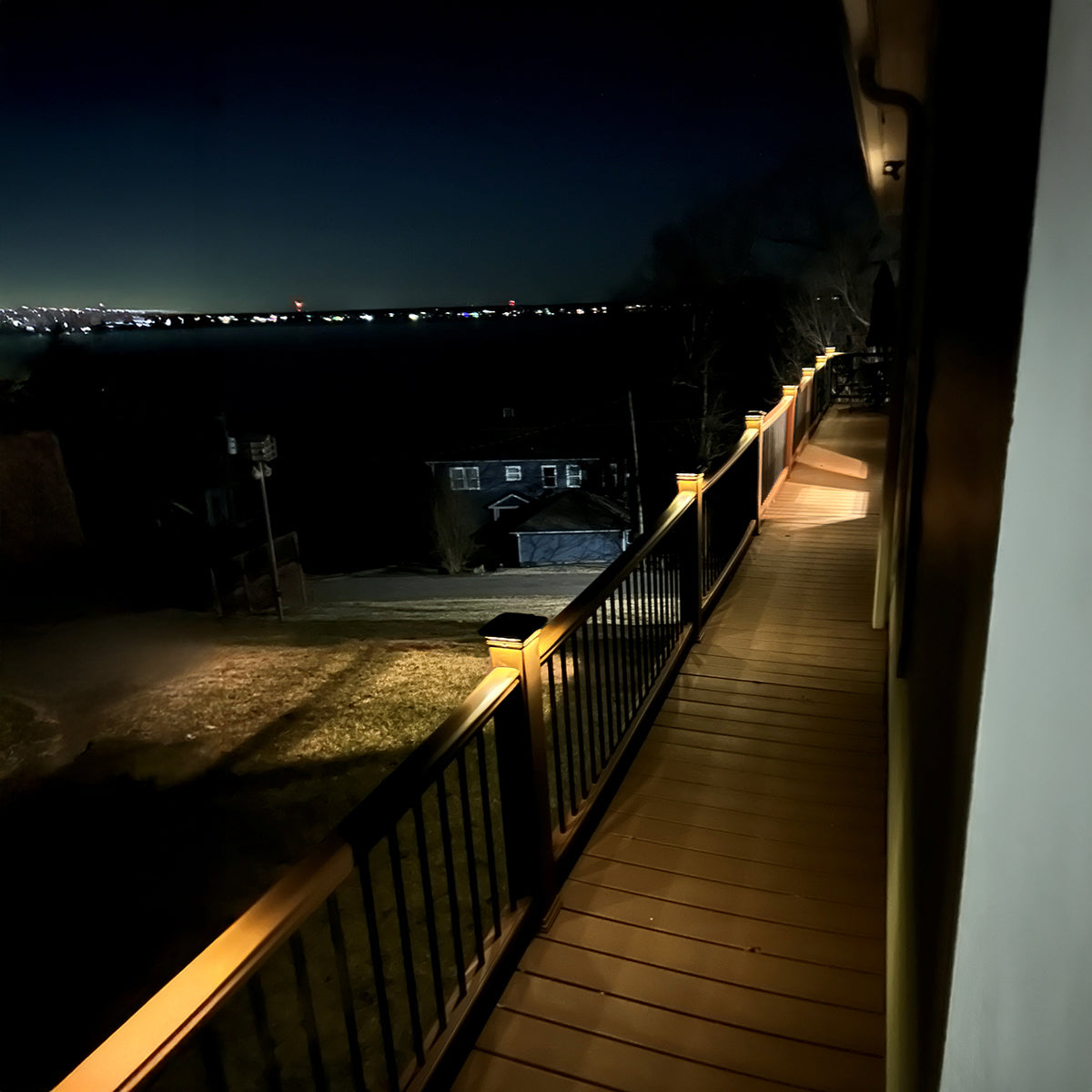 Wooden deck at night with a view of distant lights