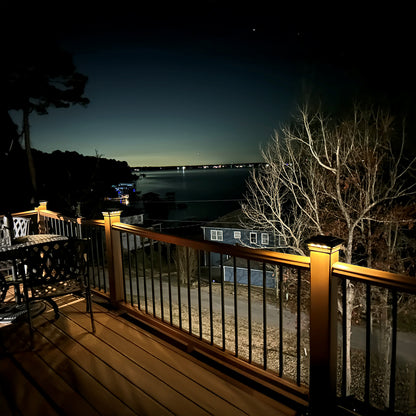 Evening view from a deck overlooking a body of water with lights on.